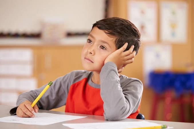 Niño realizando una tarea escolar acompañado por un adulto.